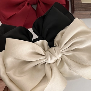 Close-up of premium satin bow hair clips in beige, black and wine red elegant silk texture