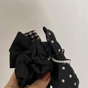 Détail d'un chouchou à nœud multicouche avec motif pied-de-poule, pois et perles