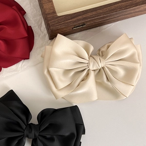 Macro detail of elegant satin bow hair clips in wine red, beige, and black colors