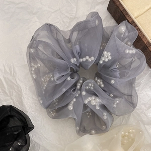 Macro-opname van grijze organza scrunchie met witte parels op getextureerde achtergrond