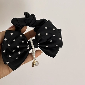 Détail d'un chouchou vintage à pois noirs avec grand nœud et pendentif en perles