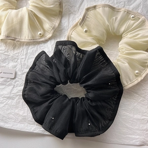 Detail of organza scrunchies with white pearls in black and off-white colors