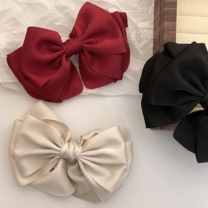 Detailed view of large satin bow hair clips in burgundy, black and champagne colors