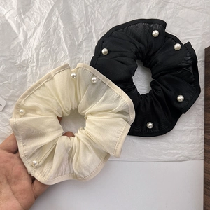 Close-up of elegant organza scrunchies with white pearl trim in black and beige colors