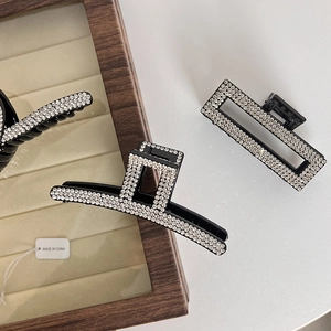 Detail of elegant hair claw clips with white crystal rhinestones on a black resin base