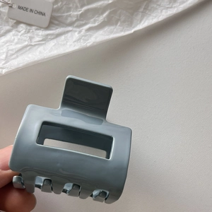Detailansicht der blau-grauen Haarklammer mit quadratischem Hohlraum und glänzendem Finish