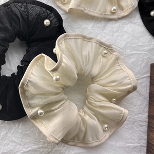 Detailed macro view of black and beige organza scrunchies with elegant pearl edge trim