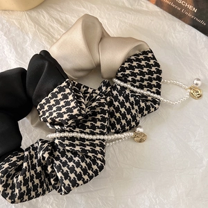 Detail of houndstooth scrunchies with pearls and gold coin charms on white background