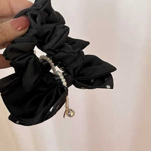 Détail d'un chouchou fait main en satin noir avec pois blancs et chaîne de perles fines