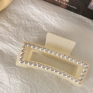 Détail d'une pince à cheveux en résine beige avec perles et strass micro-incrustés
