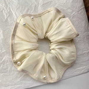 Detail of off-white organza scrunchie featuring smooth fabric and elegant pearl accents