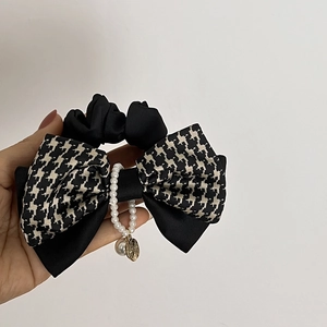 Détail d'un chouchou noeud élégant avec motif pied-de-poule et perles blanches