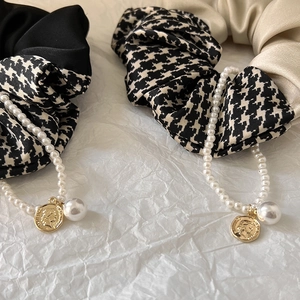 Detailed close-up of retro houndstooth scrunchies with satin texture and pearl charms