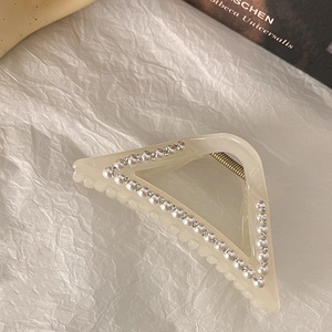 Gros plan d'une pince à cheveux avec perles et strass sur du papier froissé doux