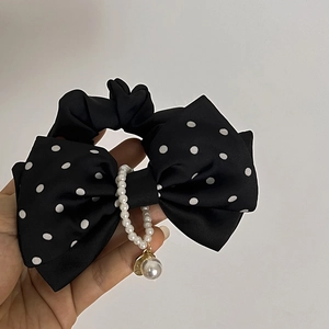 Détail d'un chouchou noeud à pois noirs avec perles et breloque dorée élégante