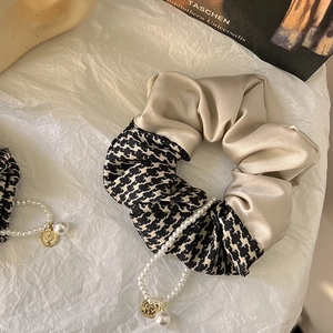 Detail of silk satin scrunchie with houndstooth pattern, pearls and coin charm