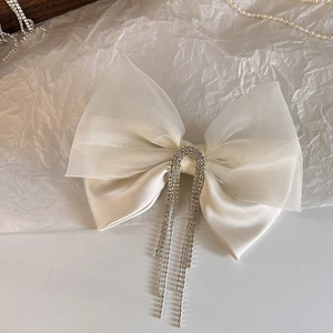 Close-up of vintage mesh bow hair clip with luxury rhinestone tassels on white background