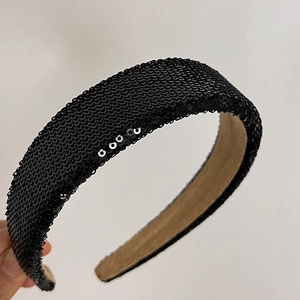 Detail of wide headband featuring black shimmering sequins and soft brown suede lining