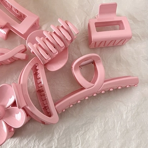 Five assorted cream pink hair claw clips in various shapes on white paper background
