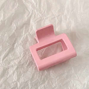 Detail view of the pink square hollow hair claw clip on white textured paper