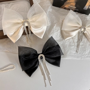 Detail of vintage mesh hair bow clips with long rhinestone tassels on textured background