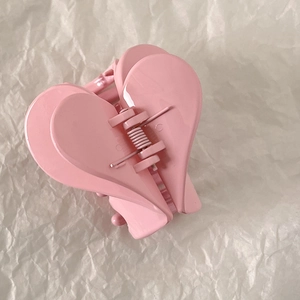 Detailed view of a glossy light pink heart-shaped hair claw clip with metallic spring