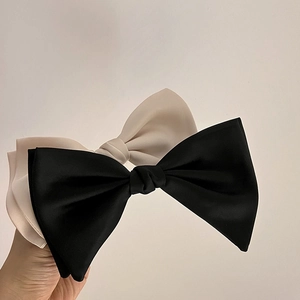 Detail of oversized matte satin double-layered bow hair clip in black and off-white colors