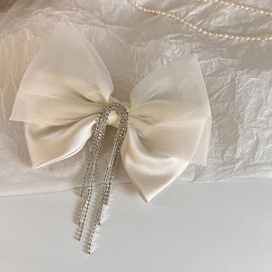 Close-up of elegant double-layered bow hair clip with sparkling rhinestone fringe and pearls