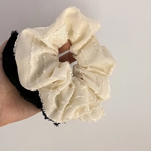 Close-up of fluffy two-tone beige and black scrunchie showing fabric texture and frayed edges