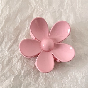 Detailed view of a glossy pink flower hair claw clip on white textured paper background