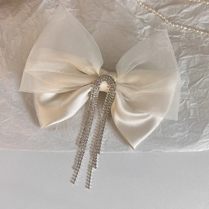 Detail of white satin bow hair clip with sparkling rhinestone fringes and crystal buckle