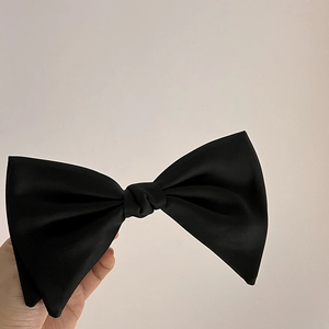 Detail of the layered black satin bow hair clip showing elegant hand-knotted texture