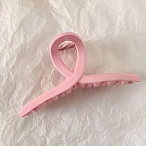 Detail showing the pink claw clip with metal spring on textured white paper