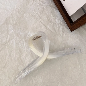 Dettaglio molletta per capelli bianco crema traslucido con molla su carta materica bianca