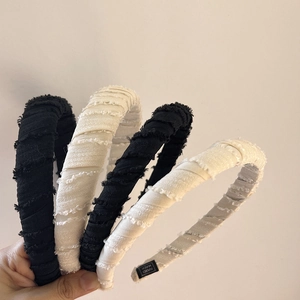 Close-up of handmade fabric headbands in black and beige with frayed texture details