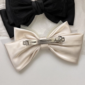 Detail of satin bow hair clip showing smooth fabric texture and sturdy metal spring back