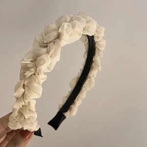 Detail of beige pleated chiffon fabric texture on a slim headband with non-slip base