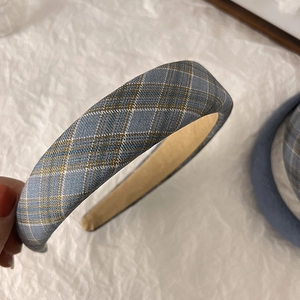 Gros plan du bandeau large vintage à carreaux bleus et dorés sur tissu blanc