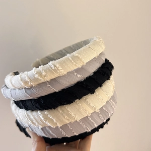 Close-up of thick sponge headbands in white, grey, and black colors with textured fabric