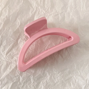 Close-up of pink shark hair claw clip with glossy finish on a textured background
