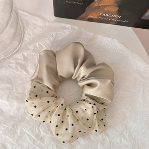 Close-up of champagne and beige polka dot scrunchie in elegant satin and chiffon fabrics