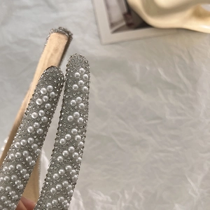 Detailaufnahme der Strass- und weißen Perlenverzierungen auf einem silbernen Haarreif