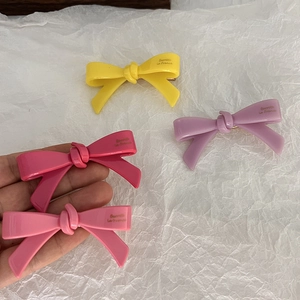 Lot de quatre barrettes en forme de nœud colorées en résine rose, jaune et violette