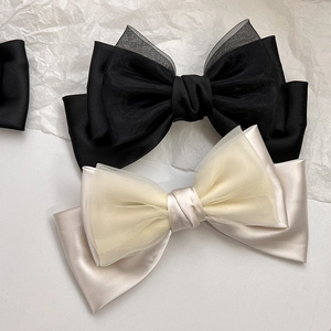 Close-up of the elegant dual-layer satin and mesh bow hair clip in black and champagne