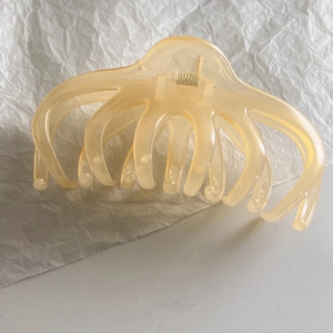 Macro detail of amber translucent octopus hair claw with metallic gold spring