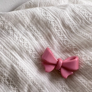 Gros plan détaillé d'une barrette noeud rose doux sur un fond en tissu texturé