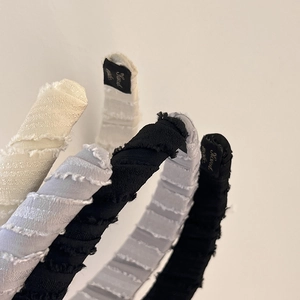 Close-up of textured fabric headbands with raw edges and golden brand label detail