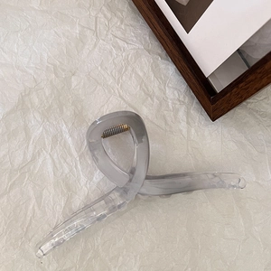 Dettaglio di un fermaglio per capelli grigio traslucido con design a torsione su carta