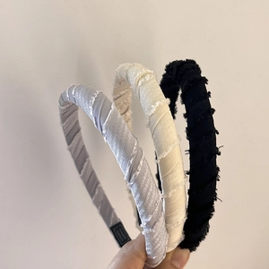 Detailed view of handmade fabric headbands with fringe edges in grey, beige, and black