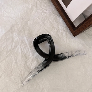 Dettaglio di un grande fermaglio per capelli in resina con sfumatura nero-trasparente